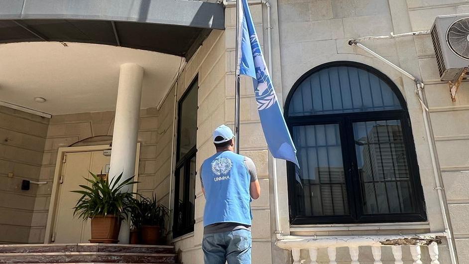 A UN staff is is lowering the UN flag at a UN building in Yemen