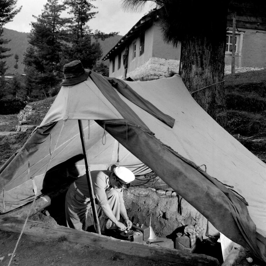 Person in uniform works with communication equipment inside a pitched tent with an open flap.